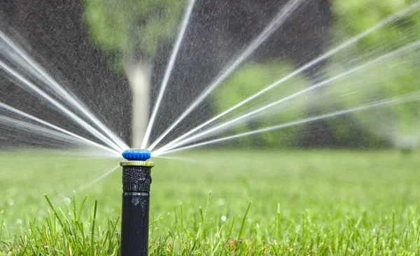 Automatisk sprinkler system vattna gräsmattan på en bakgrund av grönt gräs — Stockfoto