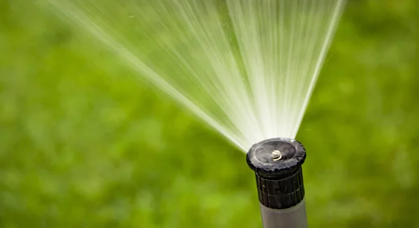 Sistem sprinkler otomatis menyiram rumput di latar belakang rumput hijau — Stok Foto