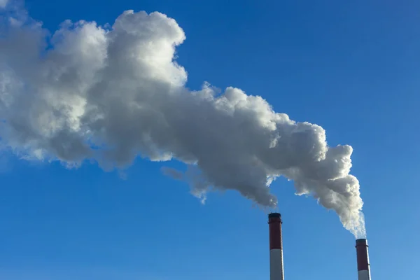 De pijp van de plant straalt schadelijke stoffen in de atmosfeer. Close-up op een hemelachtergrond — Stockfoto