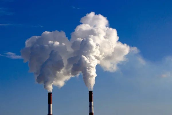 De pijp van de plant straalt schadelijke stoffen in de atmosfeer. Close-up op een hemelachtergrond — Stockfoto