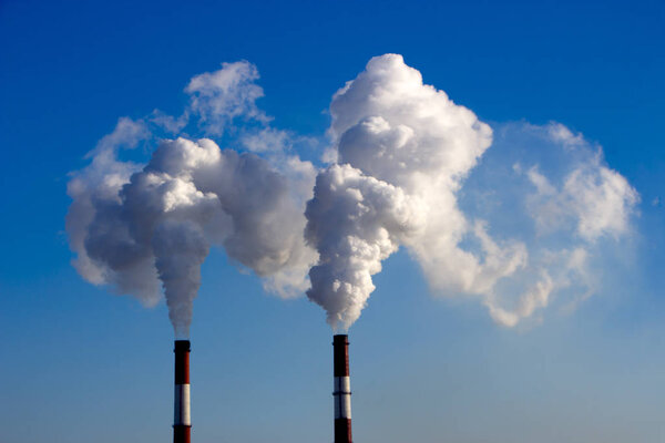 The pipe of the plant emits harmful substances into the atmosphere. Close-up on a sky background