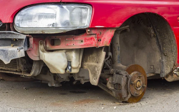 Coche sin ruedas cuesta en ladrillo, viejos frenos de coche oxidados en mal estado . — Foto de Stock