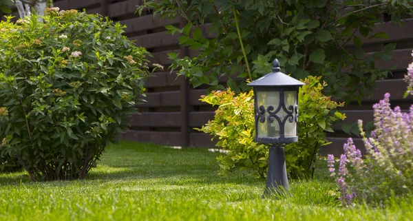 stock image garden lamp, made in the Middle Ages, on a lawn with a juicy green grass