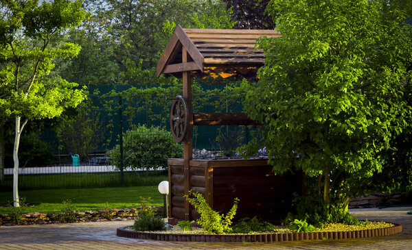 Старый деревянный колодец, рядом с которым растет куст
