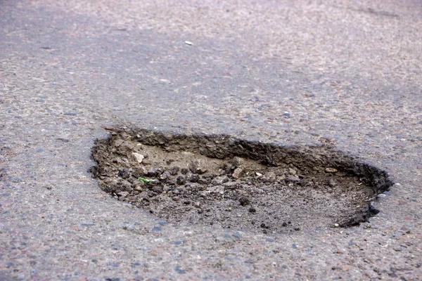 There are many potholes on the road close up — стоковое фото