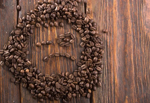Sorriso em forma de grãos de café torrados em fundo de madeira branca — Fotografia de Stock