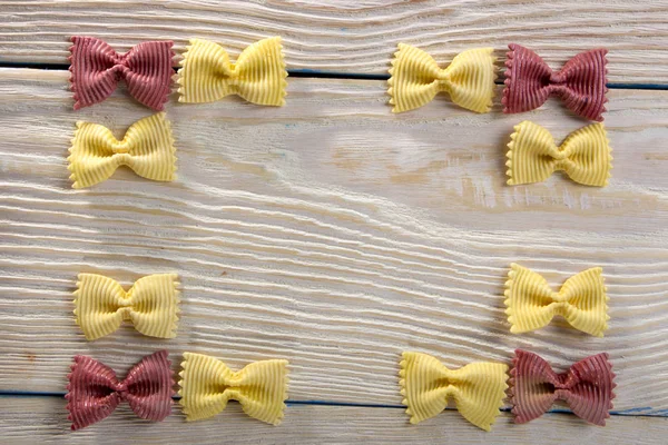 A frame of butterfly pasta on a wooden background — Stock Photo, Image