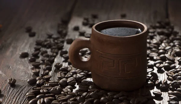 Clay cup with coffee on the background of grains — Stock Photo, Image