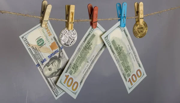 Money laundering concept. Yellow clothes peg hold Bitcoin and one hundred dollar banknotes — Stock Photo, Image