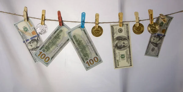 Money laundering concept. Yellow clothes peg hold Bitcoin and one hundred dollar banknotes — Stock Photo, Image