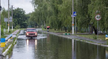Haziran 21, Vyshenky Ukrayna. Sonuçları duş. Su dolu bir cadde üzerinde büyük bir su birikintisi üzerinden araba su sıçramalarına.