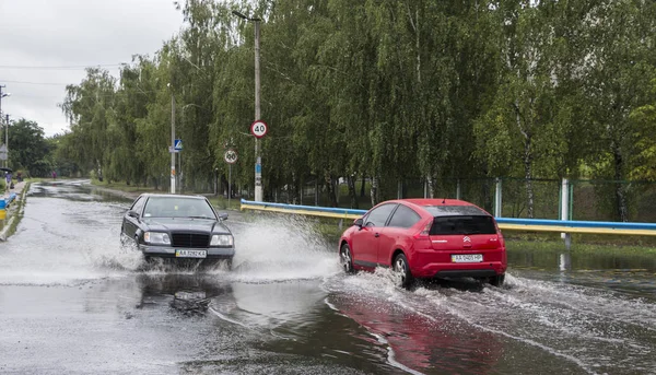June 21, Vyshenky Ukraine. Consequences of the shower. Car splashes through a large puddle on a flooded street. — Stock Photo, Image