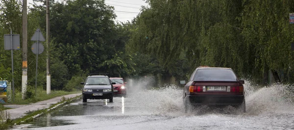 21 juni, Vyshenky Ukraina. Konsekvenserna av duschen. Bil stänk genom en stor pöl på en översvämmad gata. — Stockfoto