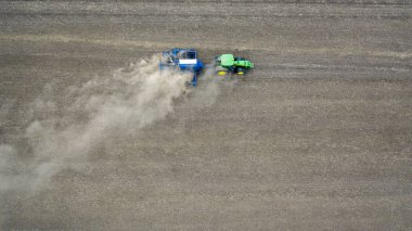 Traktör tarlayı eker, tozu havaya kaldırır..