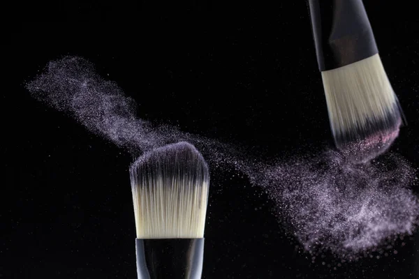 Conceito, maquilhagem. Dois fabricantes de escovas espalham pó em um fundo preto . — Fotografia de Stock
