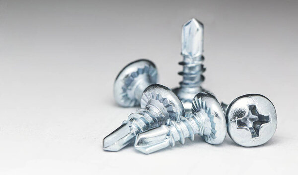 Несколько белых саморезов на белом фоне

