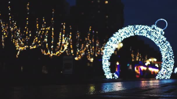 Defocus Christmas lights on the street arch with garlands in the shape of a Christmas ball. — Stock video