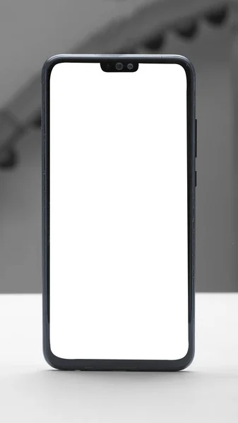 Vit smartphone med vit blank skärm på en vit plastyta — Stockfoto