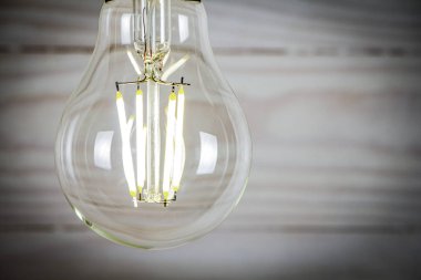 Ahşap arka planda parlayan öncü ampul yakın plan.