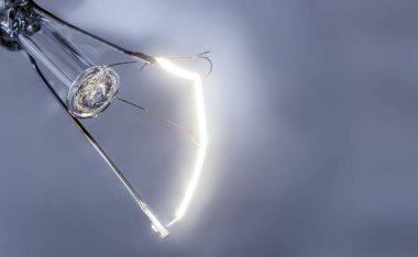 Gri arka planda parlak, parlak, parlak bir lamba teli.