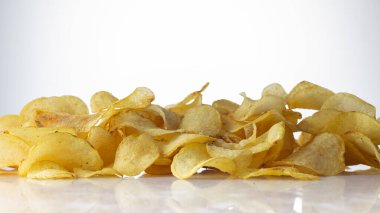 Beyaz arka planda altın rengi patates cipsi.