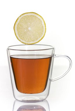 Beyaz arka planda cam termo bardakta limonlu çay..