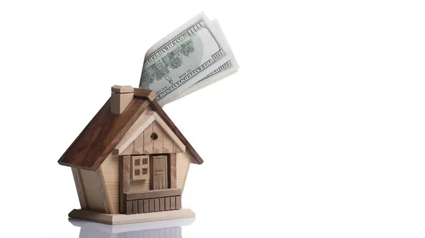 The concept of accumulating savings for the purchase of real estate. Small wooden lodge piggy bank, and 100 banknotes. — Stock Photo, Image