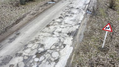 Büyük çukurlar asfalt yolda suyla doludur.