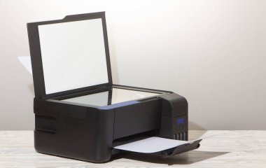 Black copier on white wooden table, closeup.