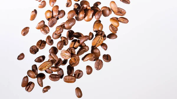 Falling coffee beans, in motion, on a white background. Selective focus. — Stock Photo, Image