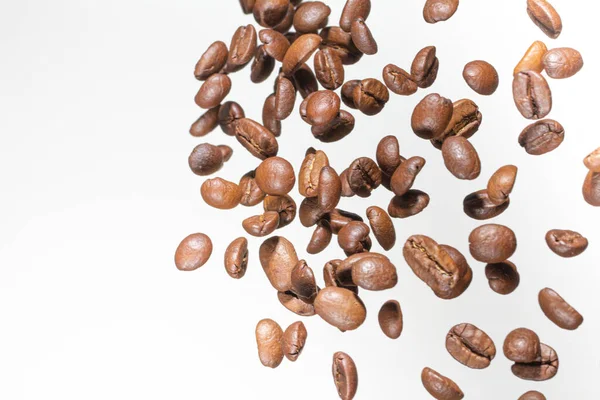 Fallende Kaffeebohnen, in Bewegung, auf weißem Hintergrund. Selektiver Fokus. — Stockfoto