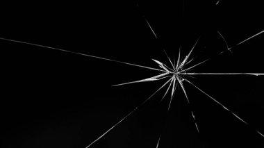 Siyah arka planda camda yuvarlak çatlaklar var. Merminin cam yüzeyindeki delik..