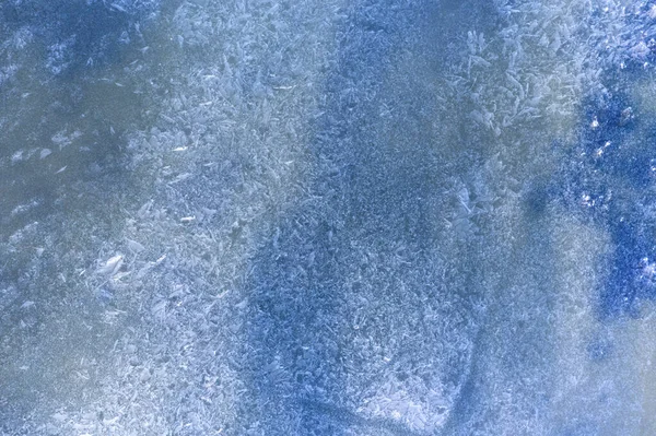 View from the drone to the surface of the frozen lake. Blue texture of pure ice. High detail. Cold abstract background for designers.