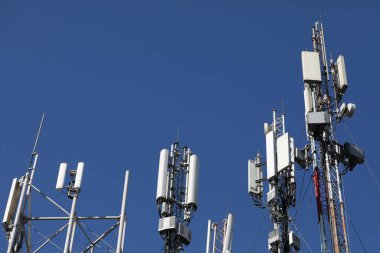 Many mobile towers, satellites and repeaters on a background of blue sky. Wireless communication equipment. clipart