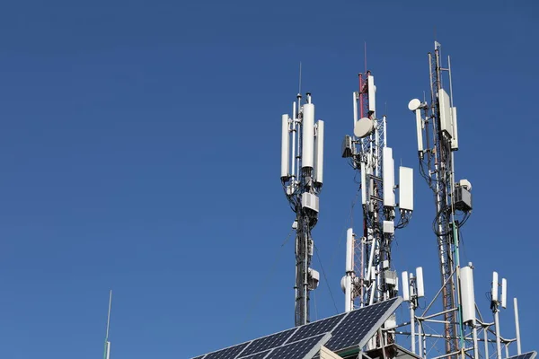 Many mobile towers, satellites and repeaters on a background of blue sky. Wireless communication equipment.
