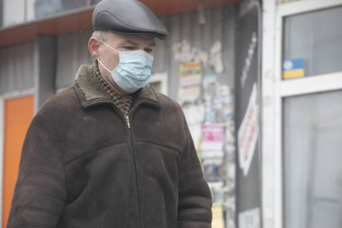 Ukrayna Kiev 23 Mart 2020: Sokakta yürüyen bir adam COVID-19 'dan korunmak için şapka ve maske takıyordu