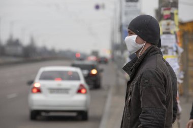 Ukrayna Kiev 23 Mart 2020: Sağlık maskeli genç adam toplu taşımayı bekliyor.