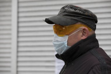 Ukrayna Kiev 23 Mart 2020: COVID-19 Coronavirus enfeksiyonundan korunmak için dışarıda maske ve şapka takan orta yaşlı bir adam.