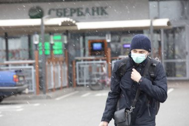 Ukrayna Kiev 23 Mart 2020: Bulutlu bir bahar gününde yüzünde Coronavirus COVID-19 maskesi olan bir adam mağazadan dönüyor.