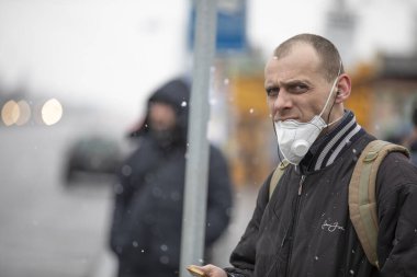 Ukrayna Kiev 23 Mart 2020: Korumalı bir maskeyle toplu taşıma durağında duran genç adam, COVID-19 Coronavirus tarafından enfekte olma tehlikesiyle karşı karşıya.
