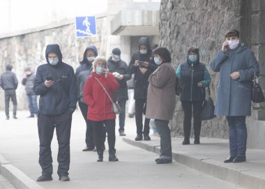 Ukrayna Kiev 23 Mart 2020: Otobüs durağındaki insanlar SARS-CoV-2 veya COVID-19 koronavirüslerinden korunmak için tıbbi maskeler takmış halde otobüs duraklarında bekliyorlar.