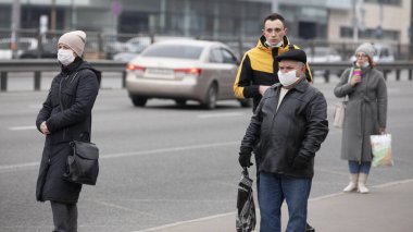 Ukrayna Kiev 23 Mart 2020: Otobüs durağındaki insanlar SARS-CoV-2 veya COVID-19 koronavirüslerinden korunmak için tıbbi maskeler takmış halde otobüs duraklarında bekliyorlar.