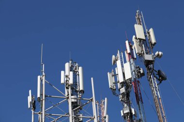 Many mobile towers, satellites and repeaters on a background of blue sky. Wireless communication equipment. clipart