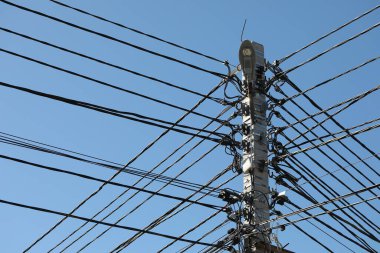 Enerji hattının beton direği, bir sürü internet, elektrik ve diğer iletişim araçlarıyla, mavi gökyüzüne karşı..