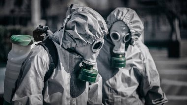 Dezenfekte ekibinden iki kişinin portresi. Yakın plan. Gaz maskeleri ve askeri koruyucu giysiler giyiyorlar..