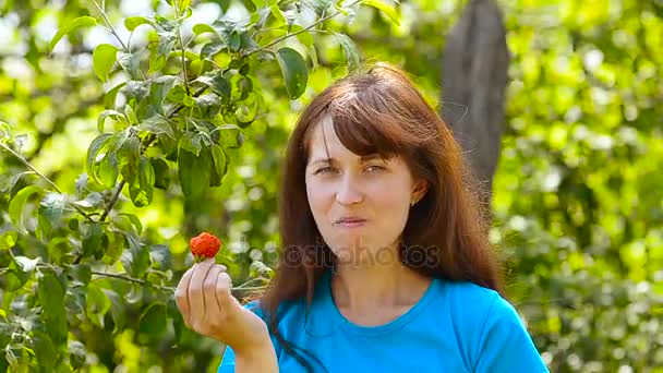 Mädchen im Garten isst rote Erdbeere auf grünem Hintergrund, — Stockvideo