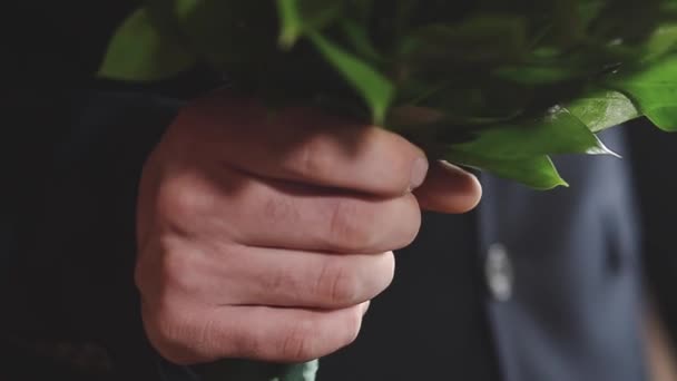 Homme en costume sombre tenant un bouquet de roses blanches et rouges, rendez-vous en gros plan — Video