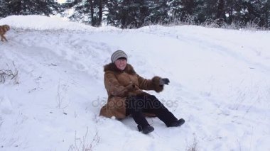 Kadın bir kar tepe ile kışın park belgili tanımlık köpek ile kadın gülüyor, Aile tatil park ile bir köpek kış sürme.