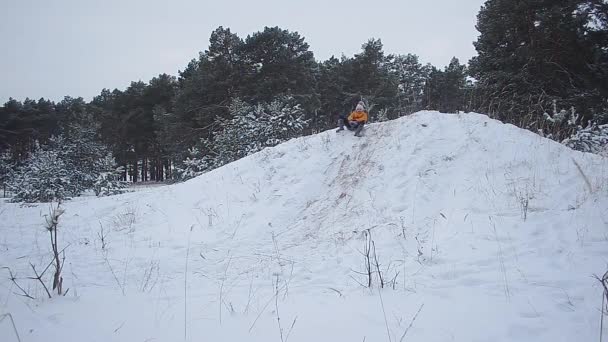 Heureuse fille souriante est roule autour des collines avec de la neige en hiver, une promenade en famille dans un parc d'hiver couvert de neige . — Video