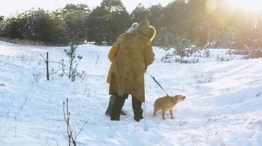 Kız ve karlı bir kış parkta bir köpekle karla kaplı ağaçlar, bir arka plan üzerinde yürüme büyükanne soğuk güneşli.
